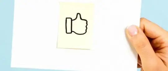 Person holding sticky note with thumbs up